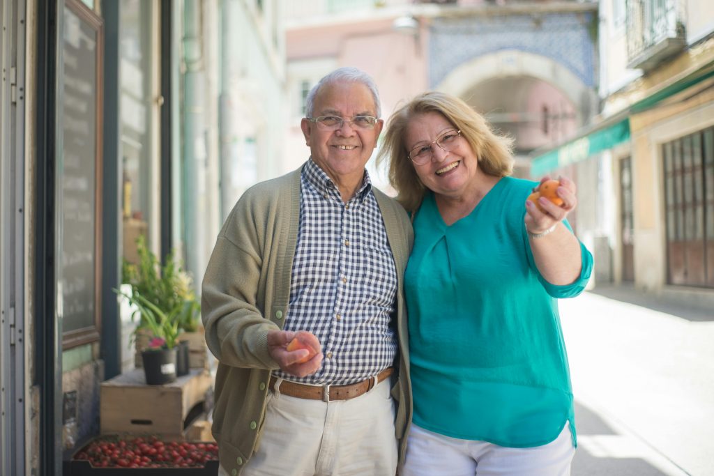 Smiling senior couple enjoying a day out shopping in a sunny Portuguese street.